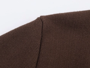 Dettaglio macro della cucitura sulla spalla di un cardigan in maglia marrone scuro