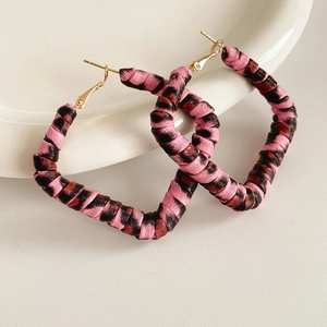 Macro view of leopard print fabric wrapped around gold diamond-shaped hoop earrings