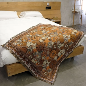 Detail of woven floral blanket with fringe edges on bed for cozy home decor
