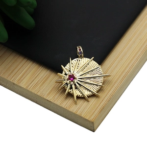 18K gold plated sunburst pendant with ruby red gemstone on a minimalist wooden base