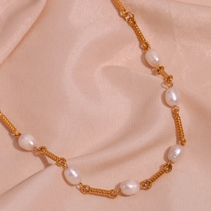 Detailed close-up of 18K gold plated spiral chain and baroque freshwater pearls on pink silk