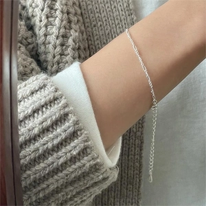 Minimalist 925 sterling silver chain bracelet on wrist with elegant knit sweater detail
