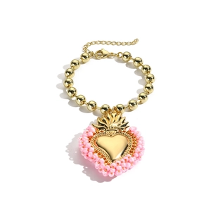 Detaillierte Nahaufnahme eines goldenen Perlenarmbands mit einem rosa Herzanhänger