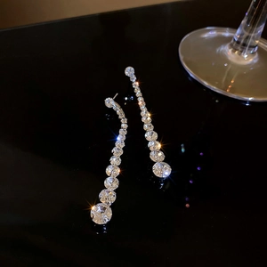 Macro shot of silver tassel earrings with gradient rhinestones on a black background