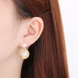 Gros plan sur des boucles d'oreilles dorées avec perles et diamants portées sur un mannequin