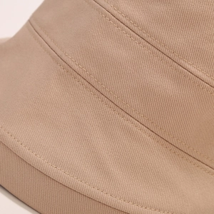 Gros plan sur la texture en sergé de coton kaki et les doubles coutures du chapeau bob