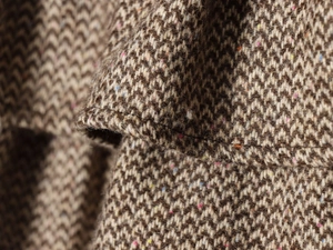 Vista macro del tessuto tweed a spina di pesce colorato con trama cashmere e cuciture precise