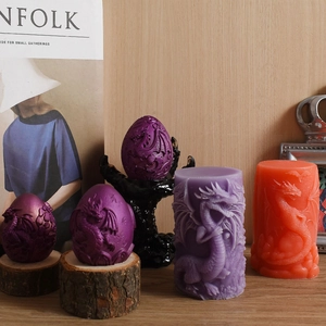 Detail of embossed dragon cylinder and dragon egg scented candles on rustic wood slices