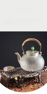 Detail of a lit candle heating a glass teapot on a vintage cast iron tea warmer base
