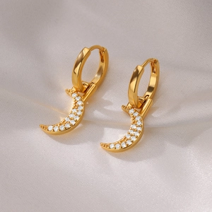 Detailed close-up of 18K gold crescent moon earrings with cubic zirconia on silk