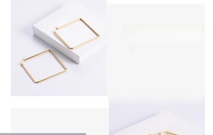 Close-up of golden geometric square hoop earrings with a polished mirror finish on a pedestal
