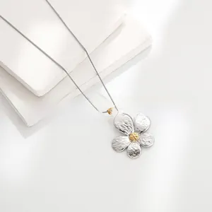 Macro detail of bicolored flower pendant with silver hammered petals and golden core