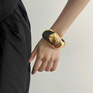 Minimalist wide gold bangle featuring a smooth mirror finish and geometric spring closure