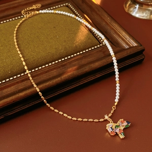 Detail of vintage necklace with pearls and gold chain featuring a colorful cross pendant