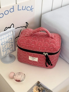 Detail of red quilted heart grid makeup bag with soft texture and sturdy top handle
