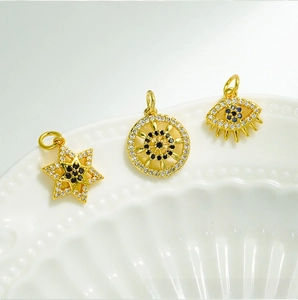 Detailed macro of 18K gold-plated bird charms with hexagon star and evil eye motifs