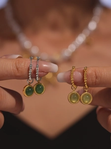 Close-up of green agate earrings in gold and silver twist hoops held by hand