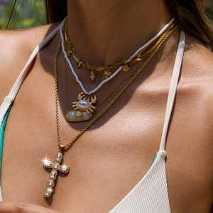 Layered stainless steel necklace with beads, crab, shell and cross pendants on model