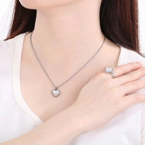 Elegant heart necklace and ring set with iridescent inlay worn by a fashion model