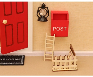 Miniature Christmas dollhouse scene with a red wooden door, mailbox, and tiny accessories