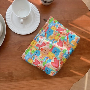 Quilted cotton pouch with colorful doodle patterns on a wooden table with coffee cup