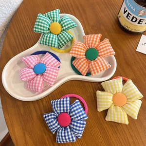Detailed view of colorful checkered fabric flower hair ties in five macaloon colors