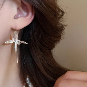 Close-up of elegant silver iris flower earrings worn by a model in a soft lighting