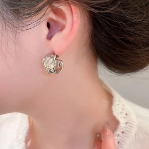 Close-up of silver pleated C-shaped earrings worn on model for a modern minimalist style
