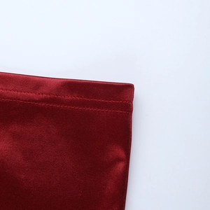 Détail macro d'une robe en satin bordeaux montrant coutures et texture côtelée