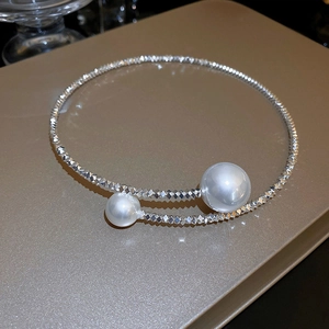 Collana girocollo irregolare con perline d'argento e due perle bianche su sfondo ruvido