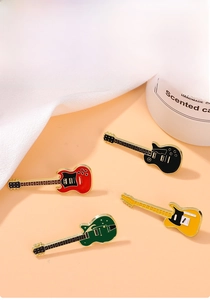 Set of four colorful guitar enamel pins in red green black and yellow on warm background