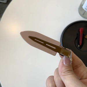Close-up of pink and brown oil painting style metal hair clip held in hand