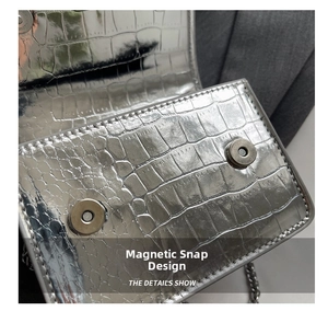 Detail of silver crocodile embossed bag showing secure dual magnetic snap closures