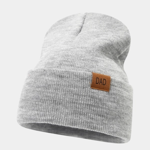 Detail of gray knitted beanie featuring a leather patch with DAD lettering for winter