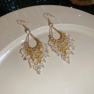 Detail of gold water-drop crystal tassel earrings with sparkling rhinestones on white plate