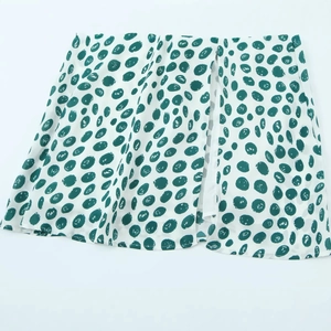 Sleeveless white midi dress with green polka dots featuring a side slit design