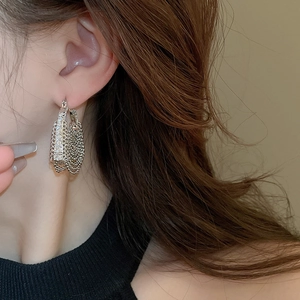 Close-up of silver mesh woven earrings worn by model for a stylish modern jewelry look