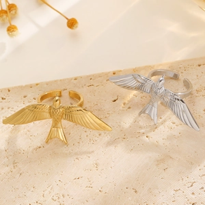 Detailed shot of gold and silver peace dove open rings with feather textures on stone