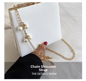 Detail of white box bag with gold metal frame and pearl embellished chain strap