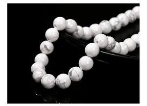 Macro shot of white howlite beads with natural grey marbling on a black background