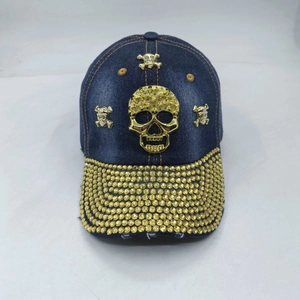 Detailed view of dark blue denim baseball cap featuring a metallic gold skull and studs