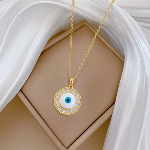 Detailed view of gold evil eye pendant with blue and white zircons on silk background