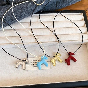 Détail de pendentifs poney colorés sur des colliers présentés dans un plateau