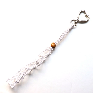 Detail of white woven cotton keychain with red wooden bead and silver heart clasp