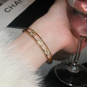Détail d'un bracelet doré orné de croix en zircon dans un décor social raffiné