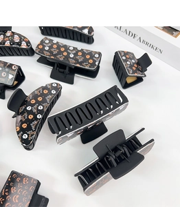 Various black Halloween hair claws with pumpkin, ghost, and skull patterns on white surface