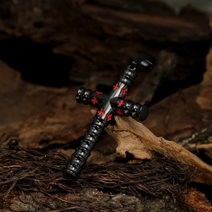Close-up of black metal cylinder cross pendant with red cross inlay on rustic background