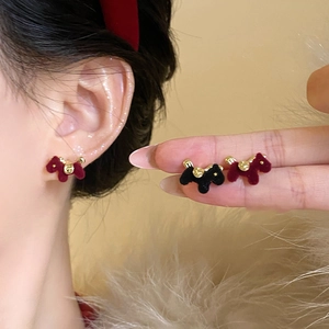 Detalle de pendientes de cachorro flocados en rojo y negro con campanas doradas