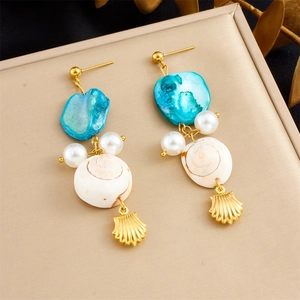 Detail of seashell earrings with blue stones, pearls, and gold-plated shell charms