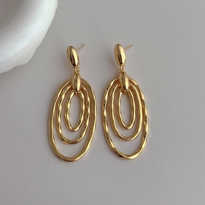 Macro shot of gold-plated triple-layered oval earrings with wavy textured finish